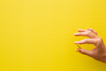 Woman's hand holding a yellow die with the number three on it