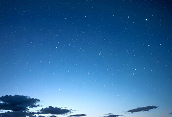 A starry night sky with a few clouds and a faint outline sunrise or sunset