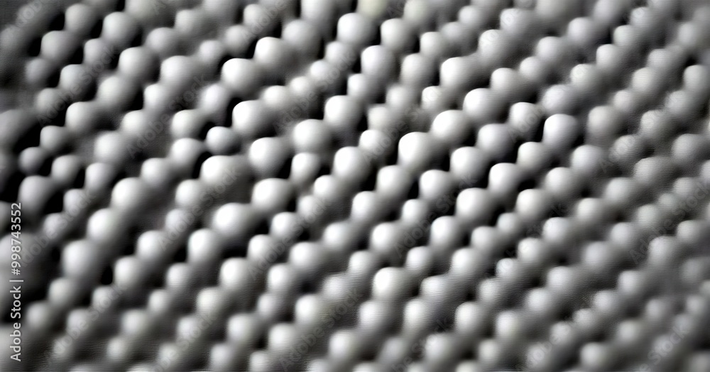 Poster a close-up view textured surface composed of numerous small, white spheres arranged in a repeating pattern The spheres vary in size and are evenly spaced, creating