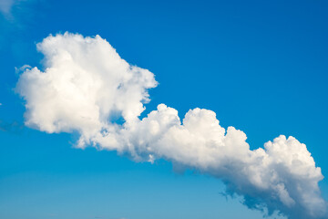 white cumulus clouds of bizarre shape in blue sky