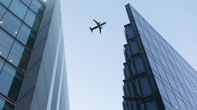 Airplane Flying Over Skyscrapers and Office Buildings in London Looking up at Plane Flying above Business Center Success Concept. 