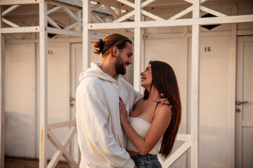 Beautiful young couple of fiancés hugging and exchanging gestures of love during a solitary outing to the sea at sunset