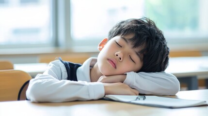 Asian bored schoolboy sleepy at school elementary education study learning tired exhausted sad upset fatigued child boy kid pupil schoolchild lying at table desk lesson class relax health problem
