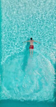 Aerial view as a man dives into the pool and swims. Slow motion