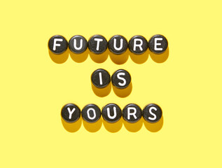 Inspirational alphabet beads on yellow background with future is yours message in bold letters.