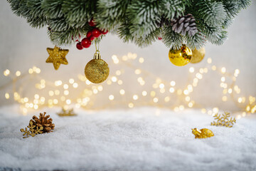 Christmas Holiday background with snow, fir tree and decorations with christmas light behind. Christmas golden balls on a winter festive background.