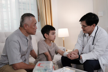 The doctor treats a wound on a boy's arm at home