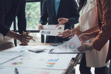 Strategic Collaboration: A diverse business team collaborates over financial data and charts in a...