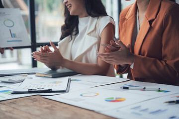 Applauding Success: Two businesswomen clap in unison, their smiles radiating positive energy. The image embodies collaboration, achievement, and the joy of shared success.  