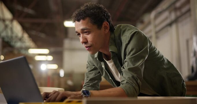 Carpentry, workshop and man with laptop checking email, inventory or creative project at small business. Warehouse, wood work and carpenter with online website for furniture, design or manufacturing