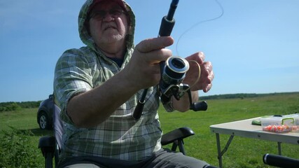 An elderly man of 60 years old, outdoors, is engaged in sport fishing, casting a rod with bait and waiting for the fish to bite. Summer, nature, fresh air, brings aesthetic pleasure and strengthens th