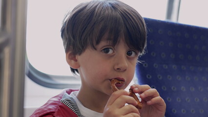 Young boy enjoying a pretzel snack on a train, candid moment of childhood joy and exploration...