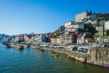 Fototapeta premium A panoramic view of Porto’s historic Ribeira district with colorful riverside buildings and traditional boats on the Douro River