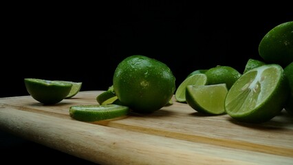 Close-up, a vibrant slice of fresh lime rests upon a rustic wooden cutting board, exuding freshness and vitality. The translucent membranes of the green lime slice placed on cutting board. Comestible.