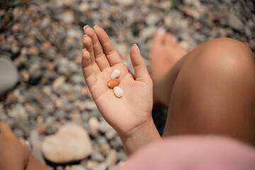 A person is holding a handful of nuts in their hand. The nuts are of different sizes and shapes, and they appear to be almonds. The person seems to be enjoying the nuts and is likely to eat them soon.