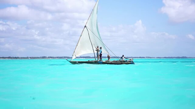 Traditional fishing boat called dhow, sail by Nungwi beach in Zanzibar, African tropical island vacation, tourism destination in Tanzania. 