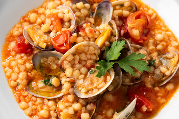 Fregula con vongole e pomodorini, pasta sarda, cibo mediterraneo 
