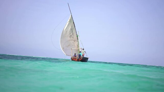 Traditional fishing boat called dhow, sail by Nungwi beach in Zanzibar, African tropical island vacation, tourism destination in Tanzania. 