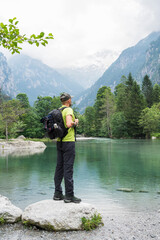 Man with backpack standing by a mountain lake.