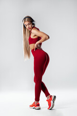 Young caucasian woman wearing headphones  active isolated on gray wall listening to music
Sexy fitness woman athletic girl