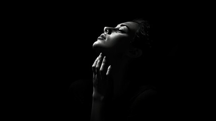 A woman's face lit by a single light source, looking upwards with her hand on her neck