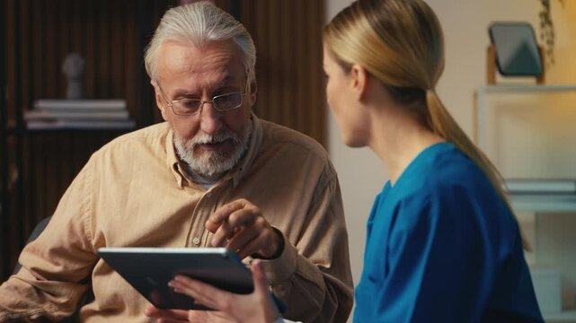 Caregiver helping senior man to create account on social media using tablet app