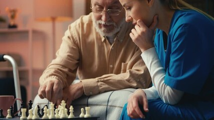 Elderly man teaching his young caregiver how to play chess game, assisted living - Powered by Adobe