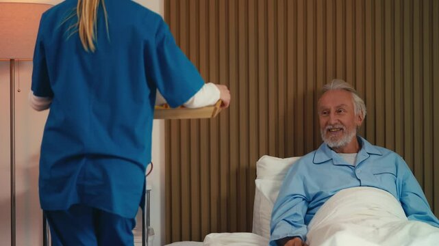 Woman caregiver bringing breakfast to bedridden senior man at retirement home