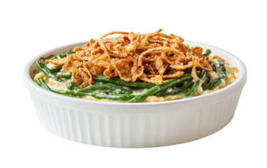 Delicious green bean casserole with creamy sauce and crispy fried onions in a white dish isolated on a white background