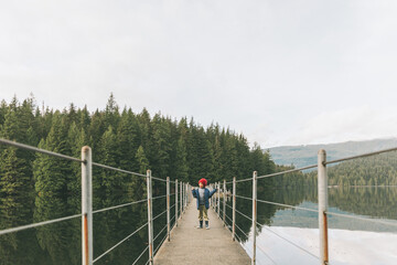 A little boy walking across a floating bridge on a lake. 