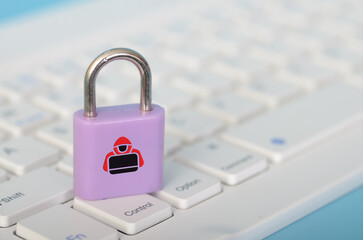 The image depicts a purple padlock with a hacker icon on it, resting on a computer keyboard, symbolizing the concept of cybersecurity threats and vulnerabilities.