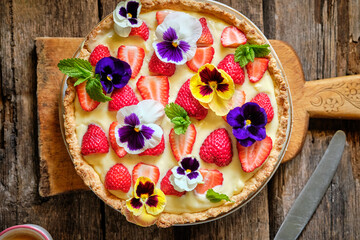 Almond tart with custard cream and strawberries decorated with edible flowers