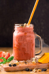 Strawberry and Mango Smoothie with Mint, Nuts and Drizzle served in jar isolated on wooden board closeup side view of healthy drink