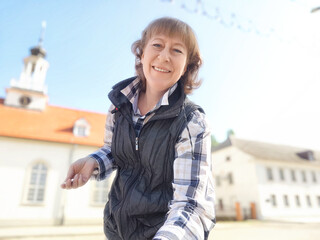 The woman enjoys her travels while taking in the charming architecture of the European town. The adventures of a middle-aged female tourist on a trip