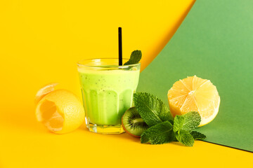 Glass of fresh kiwi smoothie with mint and lemon on colorful background