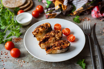 Grilled fish pieces on a white plate on a gray background. Pieces of fried fish for dinner. Close-up