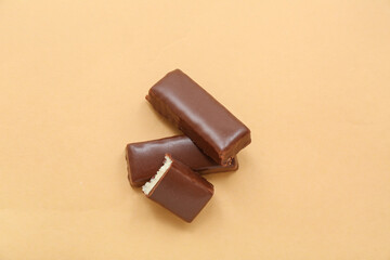 Tasty chocolate covered coconut candies on yellow background