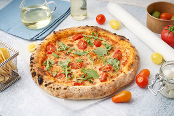 Tasty pizza Margarita with tomatoes and arugula on light blue table