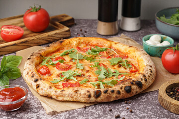Baking paper with tasty pizza Margarita and bowl of mozzarella on dark table