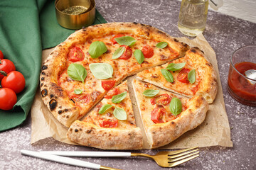 Baking paper with tasty pizza Margarita and basil on dark table