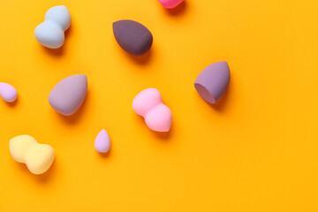 Different makeup sponges on orange background