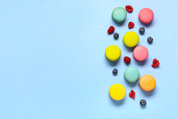 Different sweet macaroons and berries on blue background