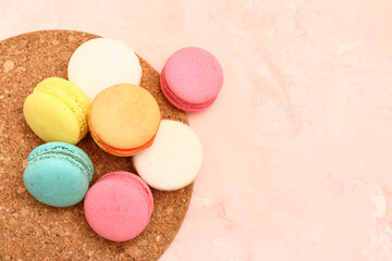 Board with sweet macaroons on pink background
