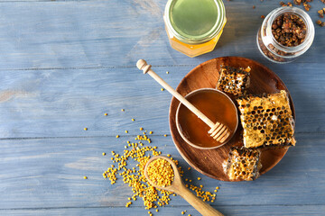Sweet honey, combs and bee pollen on blue wooden background