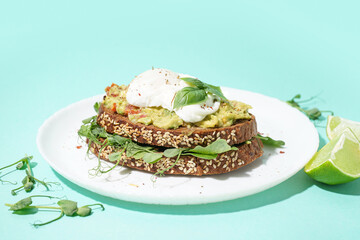 Plate of tasty sandwich with egg on turquoise background