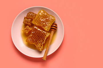 Plate with sweet honeycombs and dipper on red background