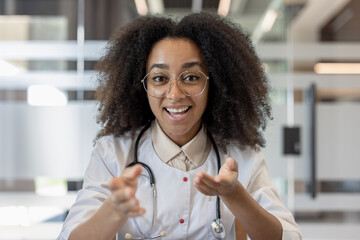Smiling female doctor engaging in a video call with stethoscope in modern office setting