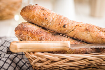 Crusty rustic baguette in basket on white table.
