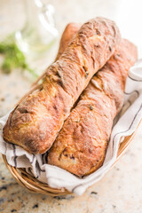 Crusty rustic baguette in basket on kitchen table.