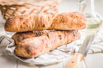 Crusty rustic baguette on white table.